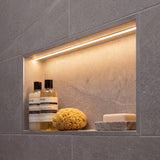 Iluminación lineal integrada en nicho de baño moderno logrando un acabado limpio y minimalista.