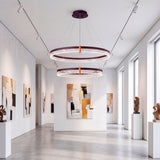 Lámpara circular en pasillo de galería iluminando obras de arte con elegancia.