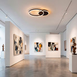 Plafón LED de gran formato en pasillo de galería iluminando obras de arte con nitidez.