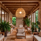Punto de luz decorativo en estancia con mobiliario de mimbre y abundante vegetación.