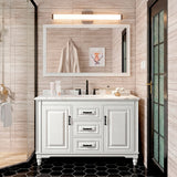 Lámpara Julieta instalada sobre mueble de baño de estilo clásico con azulejos negros.