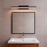 Lámpara de pared negra sobre lavabo en baño de líneas puras y diseño minimalista.