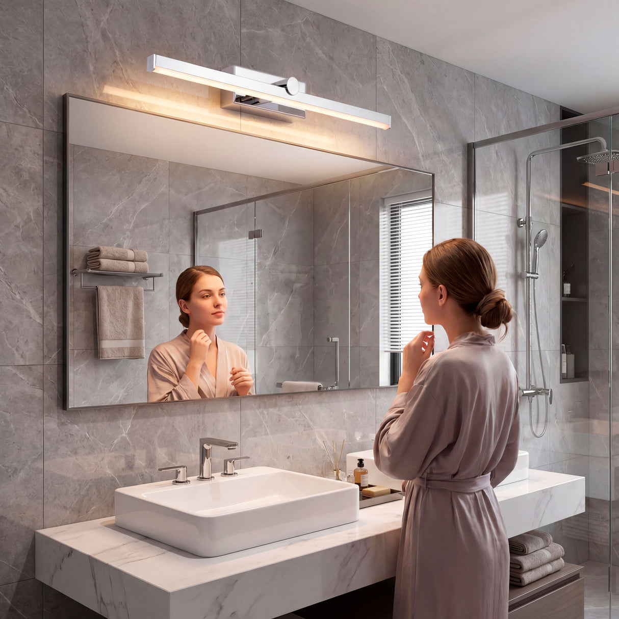 Aplique LED cromado sobre gran espejo en baño de mármol con iluminación frontal.