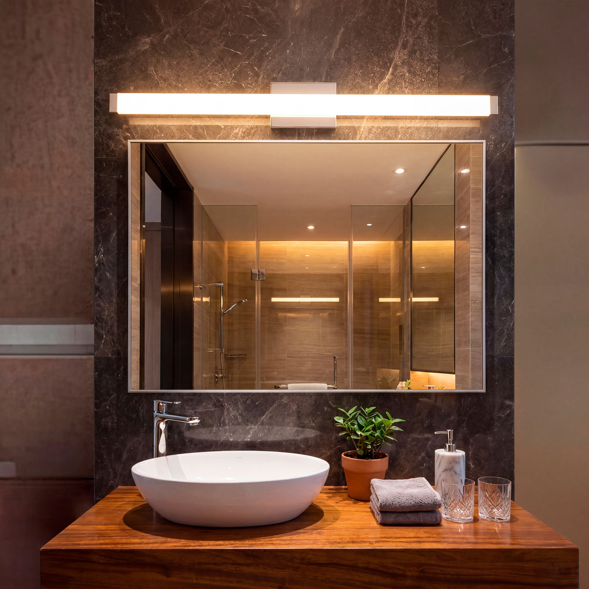 Aplique LED Julieta sobre espejo en baño elegante con revestimiento de mármol gris.
