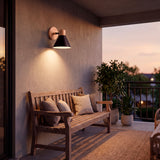 Iluminación técnica de soporte en muro para zona de estar exterior techada con ambiente cálido.