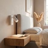 Luz puntual orientable instalada en cabecera de dormitorio garantizando confort óptico.