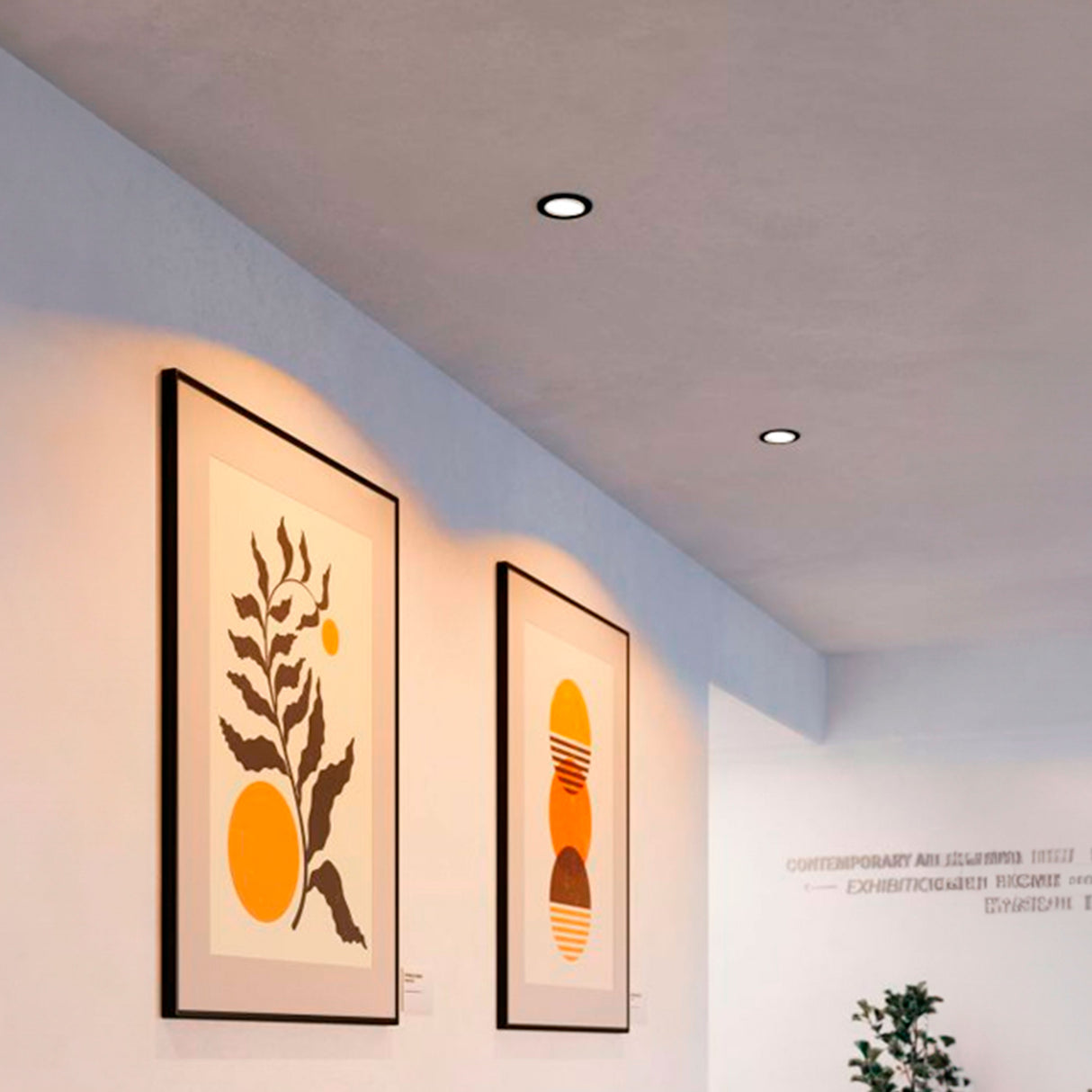 Focos empotrados negros iluminando cuadros en pasillo con luz blanca cálida y diseño limpio.