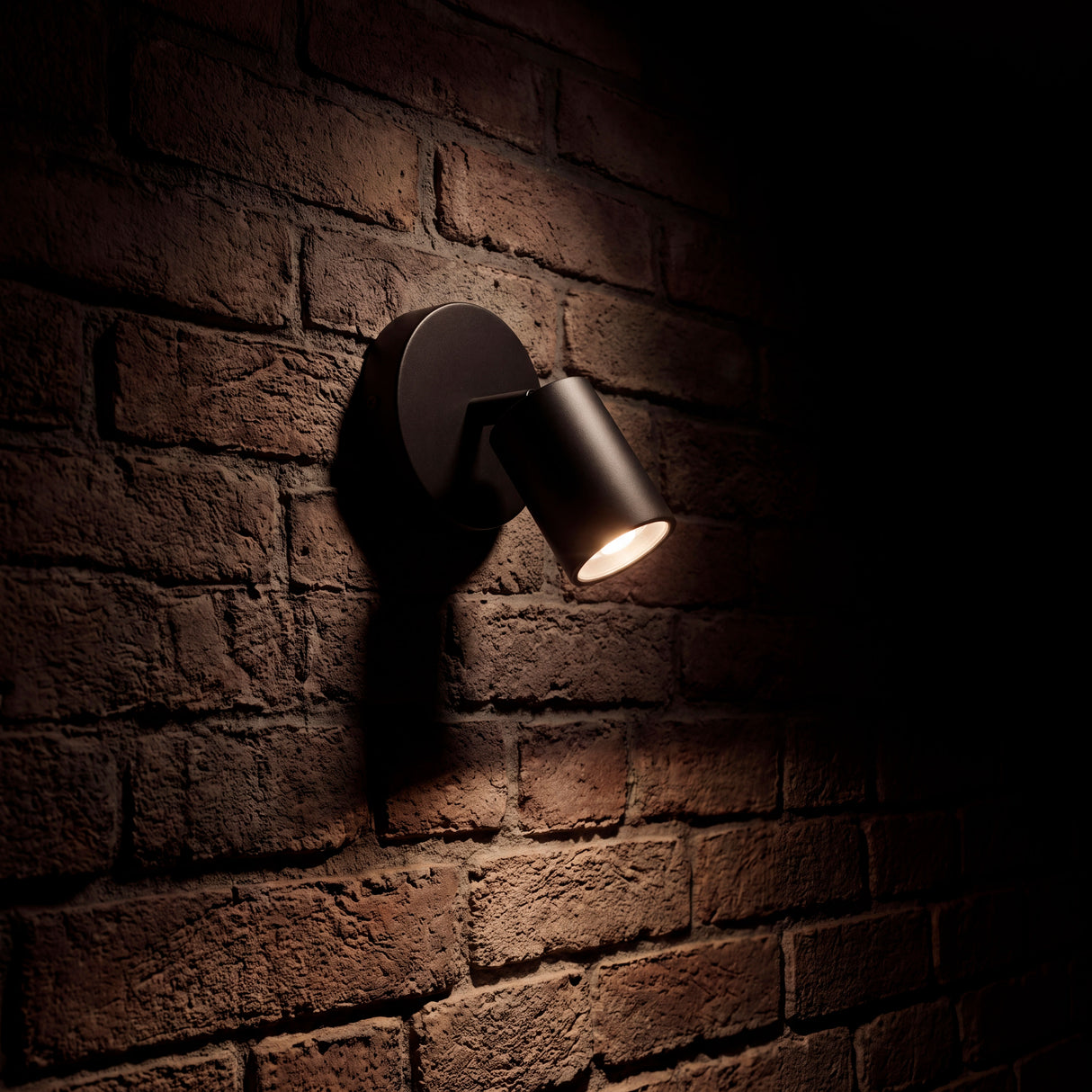 Proyección de haz de luz cálida sobre pared de ladrillo visto en ambiente de estilo industrial.