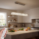 Lámpara de suspensión lineal sobre encimera de cocina con acabado cromado y luz cálida.