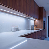 Luz técnica empotrada bajo armarios de cocina moderna para optimizar la visibilidad de trabajo.
