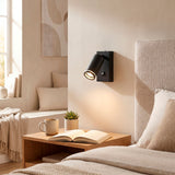 Foco de lectura negro mate instalado en cabecera de cama en habitación de hotel de diseño.