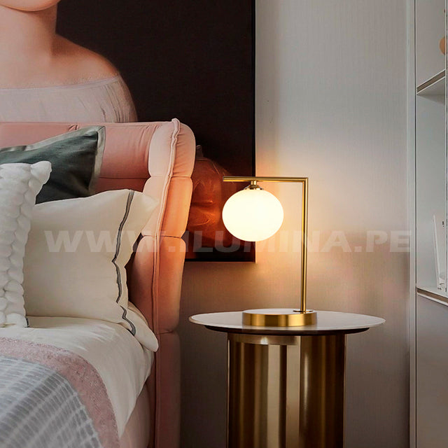 Punto de luz cálida en mesa de noche con acabado metalizado premium y estética arquitectónica.