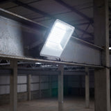 Proyectores instalados en viga de acero iluminando uniformemente el suelo de un complejo industrial.