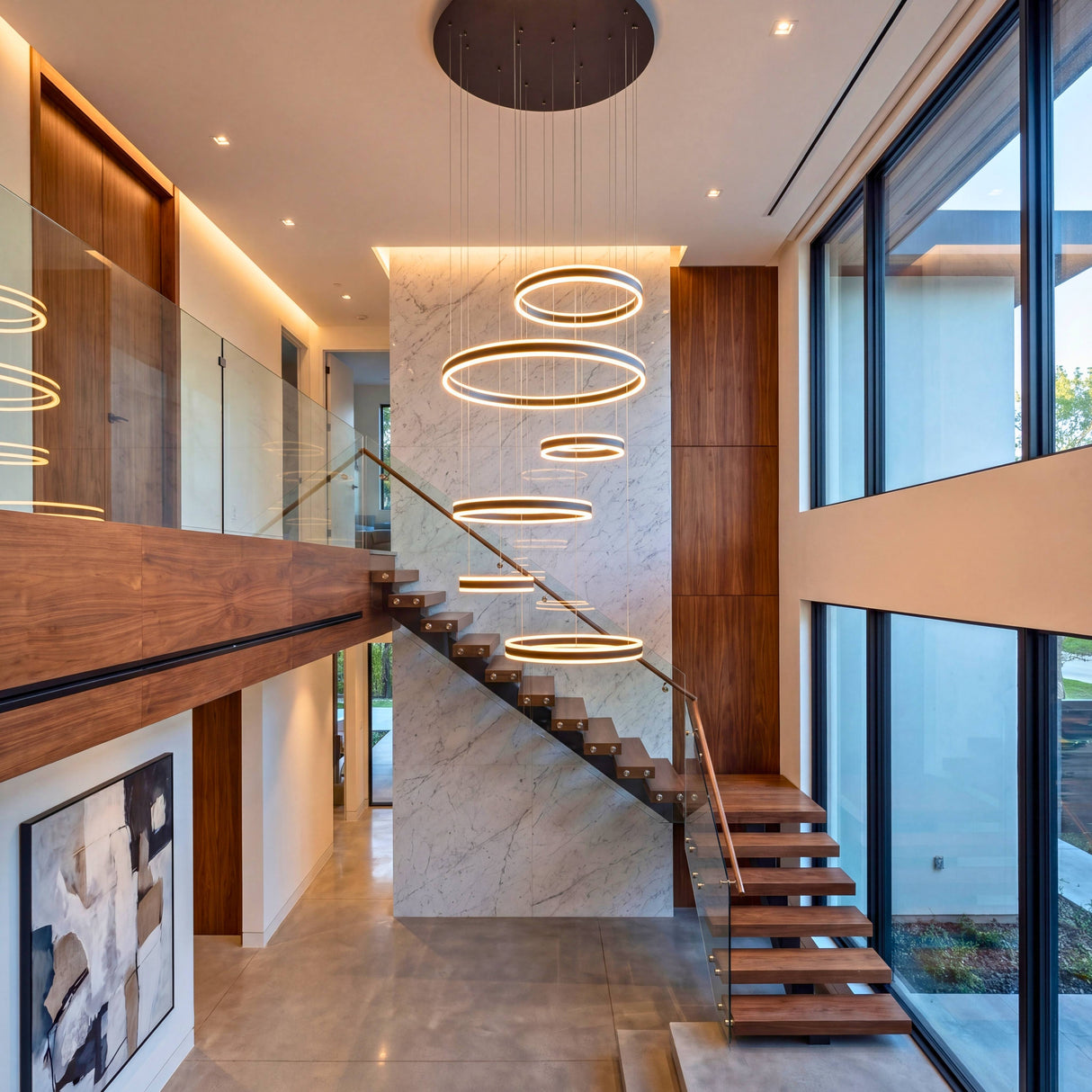 Salón moderno de concepto abierto con gran escalera iluminado por una espectacular luminaria de suspensión múltiple.