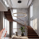 Lampara colgante de aro LED iluminando zona de escaleras de madera con diseno vanguardista.