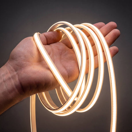 Manguera de iluminación lineal flexible de diseño minimalista encendida sobre una mano mostrando su flexibilidad.