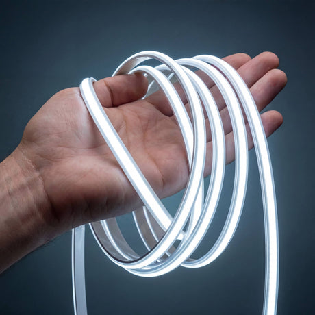 Manguera de iluminación lineal flexible de diseño minimalista encendida sobre una mano mostrando su flexibilidad.