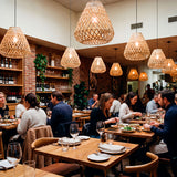 Conjunto de lámparas tejidas en restaurante de gran capacidad con techos de hormigón.