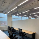 Serie de luminarias LED instaladas en serie en oficina diáfana con techo técnico visto.