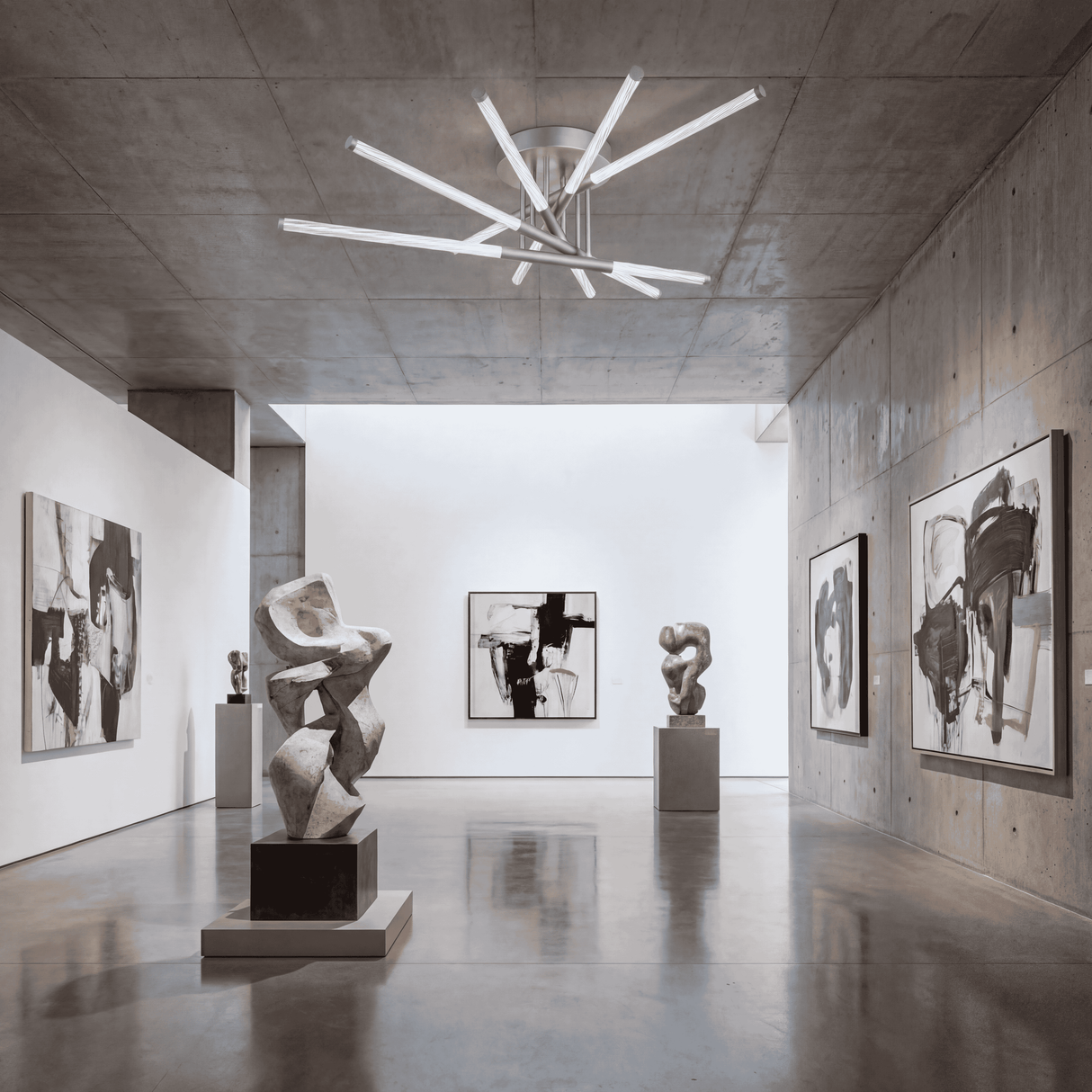 Pasillo de galería con iluminación cenital radial para destacar obras de arte.