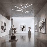 Pasillo de galería con iluminación cenital radial para destacar obras de arte.