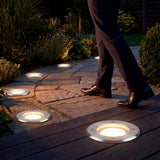 Serie de luminarias empotradas en el piso guiando un camino peatonal nocturno en un proyecto residencial.