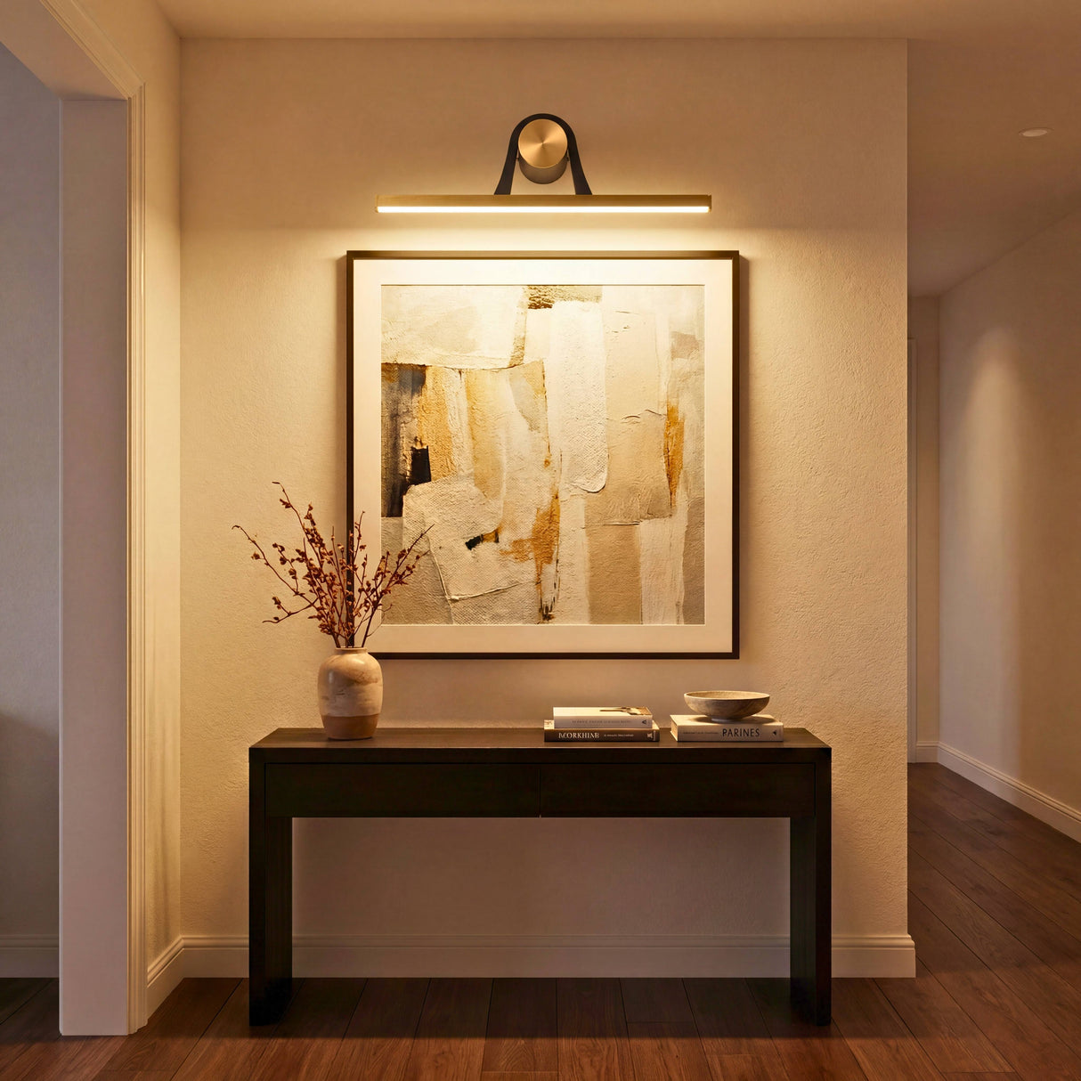 Aplique LED lineal iluminando un cuadro artístico sobre un mueble recibidor en un ambiente elegante.