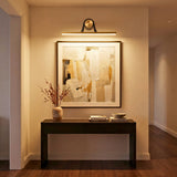 Aplique LED lineal iluminando un cuadro artístico sobre un mueble recibidor en un ambiente elegante.