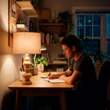 Lámpara de mesa para oficina en casa proporcionando luz difusa sobre zona de trabajo.