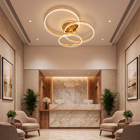 Plafón LED de diseño asimétrico dorado en área de recepción con acabados de mármol.