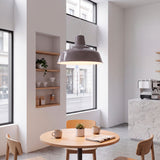 Lámpara suspendida que proporciona confort visual directo sobre mesa de madera en comedor de estilo nórdico.
