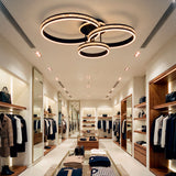 Plafón LED de tres aros negros con efecto diamante en tienda de moda de alta gama.