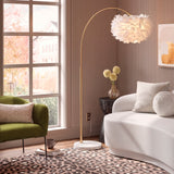 Modelo Carisma Gold extendiendo su brazo sobre un sofá blanco en un ambiente de diseño limpio.