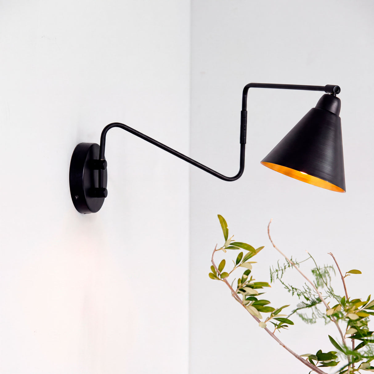 Luminaria de pared metálica negra con pantalla cónica interior dorado para arquitectura contemporánea.