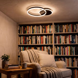 Plafón LED circular negro mate sobre zona de lectura con luz cálida y gran apertura.