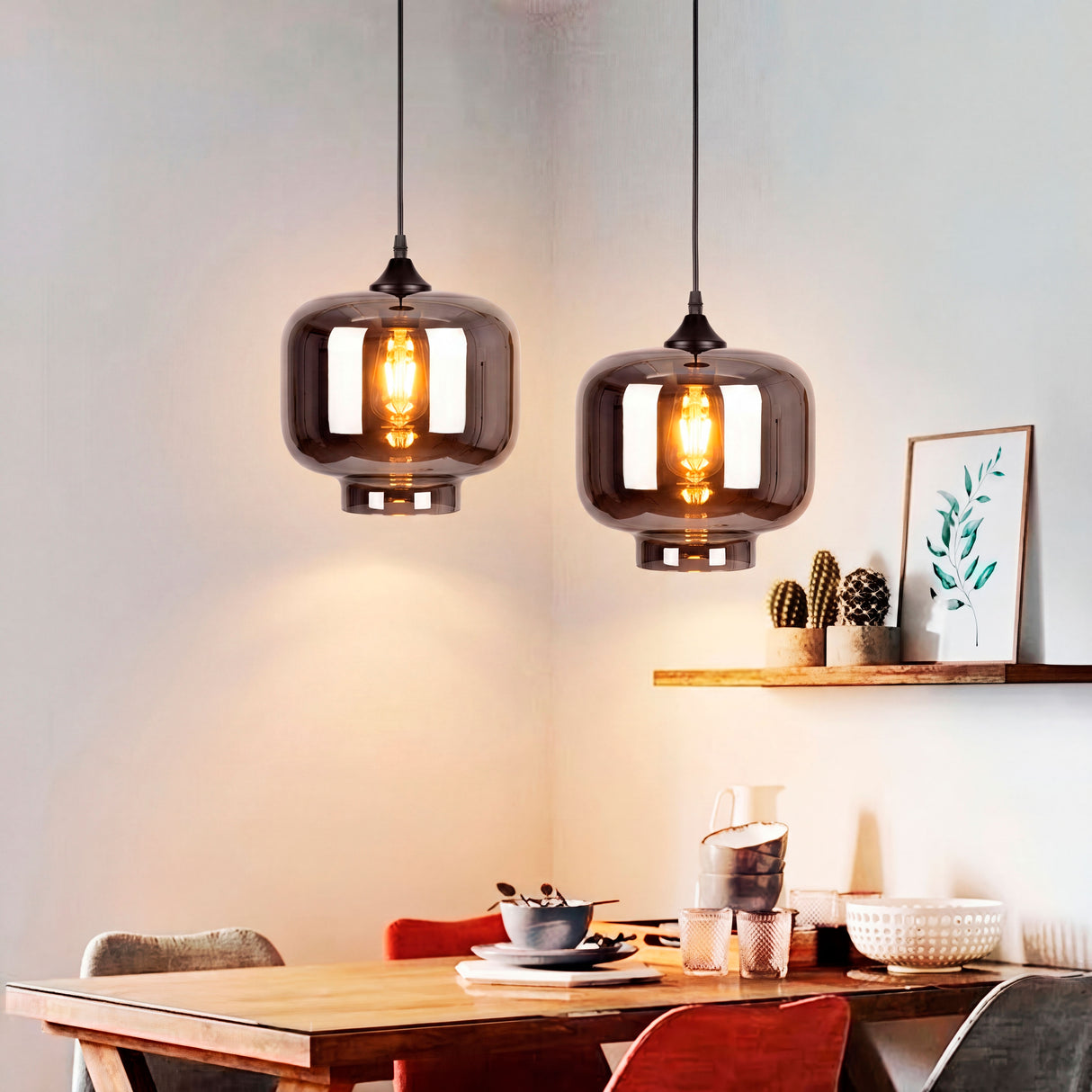 Composición de dos luminarias suspendidas a distintas alturas sobre una mesa de madera moderna.