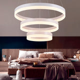 Luminaria colgante de tres anillos concéntricos con luz LED integrada en recámara moderna de gama alta.