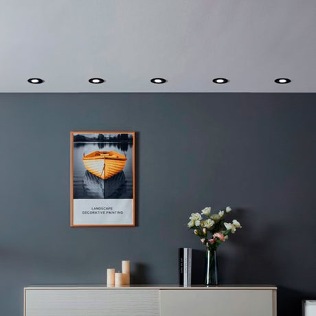 Serie de spots empotrados negros sobre pared gris oscuro creando ritmo visual y luz de acento.