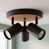 Plafón circular de sobreponer con tres focos orientables y disco decorativo en madera sobre techo claro.
