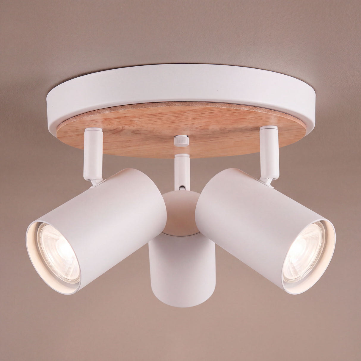 Plafón circular de sobreponer con tres focos orientables y disco decorativo en madera natural sobre techo claro.