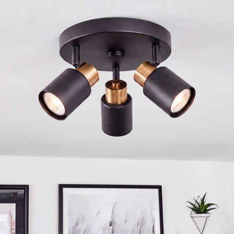 Plafón circular de tres focos orientables en negro mate con acento dorado para arquitectura contemporánea.