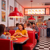 Campanas metálicas rojas que aportan luz focalizada y diseño clásico a comedores comerciales y cafeterías.