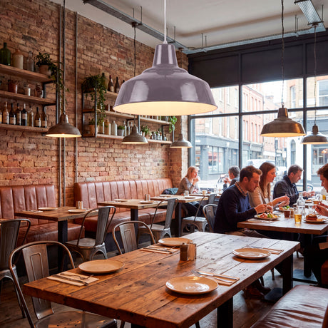Iluminación técnica de acento en comedor comercial rústico con muros de ladrillo expuesto y mesas de madera.