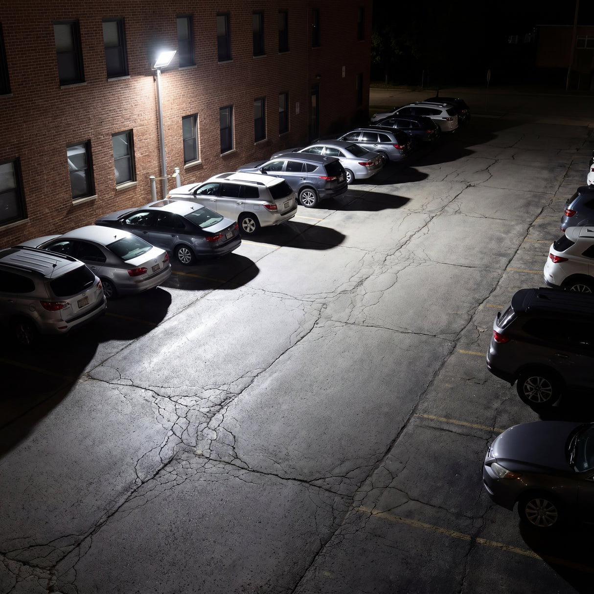 Estacionamiento exterior nocturno perfectamente iluminado para garantizar la seguridad y visibilidad.