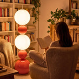 Lámpara de pie de diseño orgánico iluminando una zona de lectura junto a una estantería de libros.