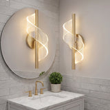 Aplique decorativo Helix Line Gold instalado junto a un espejo redondo en un bano de visitas.