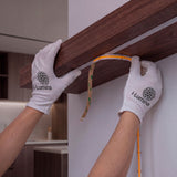Instalador con guantes técnicos adhiriendo tira lineal continua debajo de una repisa de madera.