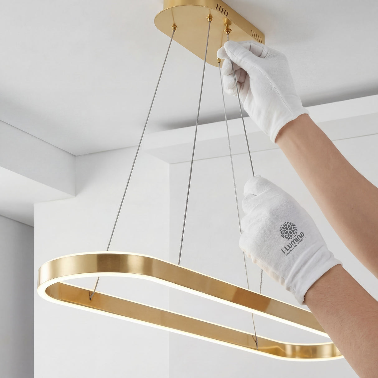 Persona instalando la base de la lámpara colgante dorada en el techo mostrando facilidad de montaje.