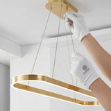 Persona instalando la base de la lámpara colgante dorada en el techo mostrando facilidad de montaje.