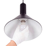 Técnico colocando una bombilla en casquillo estándar de luminaria metálica con protección manual.